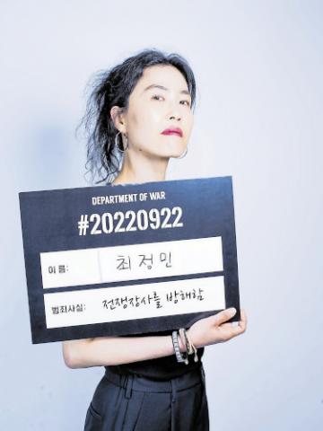 A ‘mugshot’ of South Korean activist Choi Jungmin, taken by her peace group World Without War to help raise funds for the $15,000 fine she and seven others received for protesting inside the DX arms fair near Seoul in September 2022. All the activists put on their toughest gangster expressions for their ‘mugshots’. The card reads: ‘Name: Choi Jungmin. Charge: Interfering with the War Business’. PHOTO: WORLD WITHOUT WAR