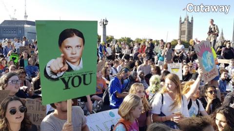 In a crowd of protesters, a demonstrator holds up a placard showing Greta Thunberg pointing her finger at 'You'.